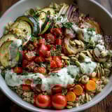 Vibrant roasted vegetables with zucchini and bell peppers top fluffy quinoa in this Roasted Vegetable Quinoa Bowl, finished with creamy tahini sauce and fresh parsley.