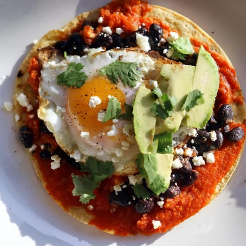 A close-up of Huevos Rancheros, featuring runny eggs and a spicy, flavorful sauce.