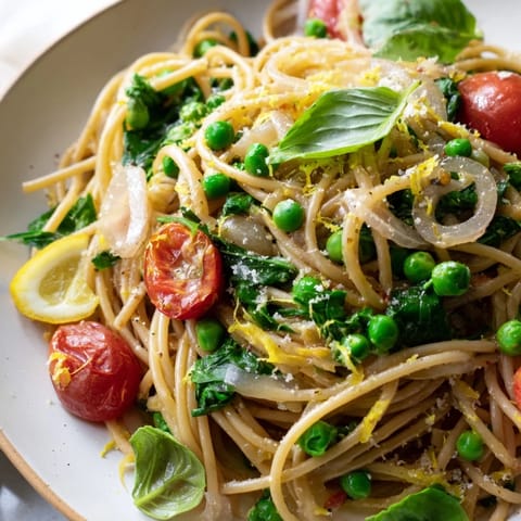 Plated Spring Veggie One-Pot Spaghetti topped with fresh basil and Parmesan for a weeknight meal.