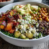 Brightly colored Fall Harvest Bowl with roasted sweet potatoes, Brussels sprouts, and crisp apples topped with almonds and feta.